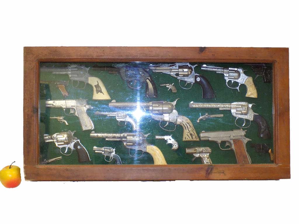SHADOWBOXED TOY CAP GUN COLLECTION: Shadowboxed Toy Cap Gun Collection. Includes: 10 Larger Pieces, 11 Miniature Pieces. Fanner 50, Hubley Remington .36, Hubley Automatic, Hubley Cowboy and Others (Some Rare). Wooden Showcase 30" x 4" x