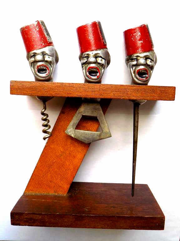 VINTAGE WAITER HEAD METAL BAR WARE CORKSCREW SET: Circa 1950's Figural Waiter / Servant Head Bar ware Set. Painted Cast Metal with Wooden Stand. Includes Corkscrew, Bottle Opener, Ice Pick.
