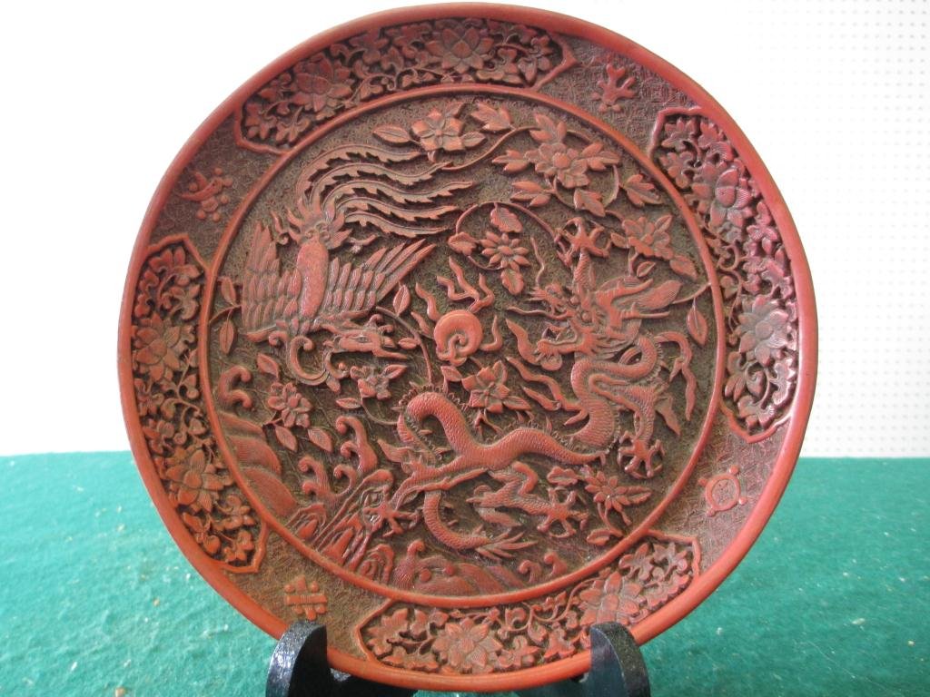 VINTAGE CARVED CHINESE SCENIC CINNABAR PLATE: Vintage Signed Chinese carved cinnabar scenic plate depicting Dragon , flying phoenix & floral motifs . D 8"