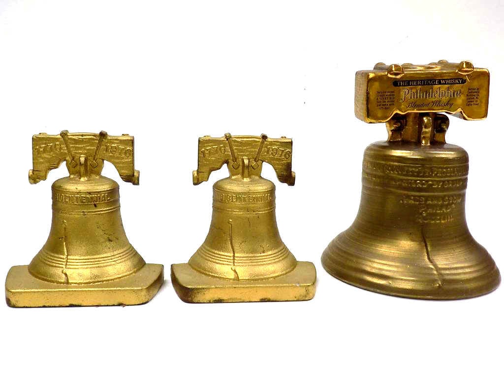 AMERICAN BICENTENNIAL BELL GILT CAST IRON BOOKENDS: Pair of American Bicentennial Bell Bookends. Gold Gilt Cast Iron. Numbered 121. 5.50" x 5.25" Approximately 7 lbs. Along with Whiskey Decanter.
