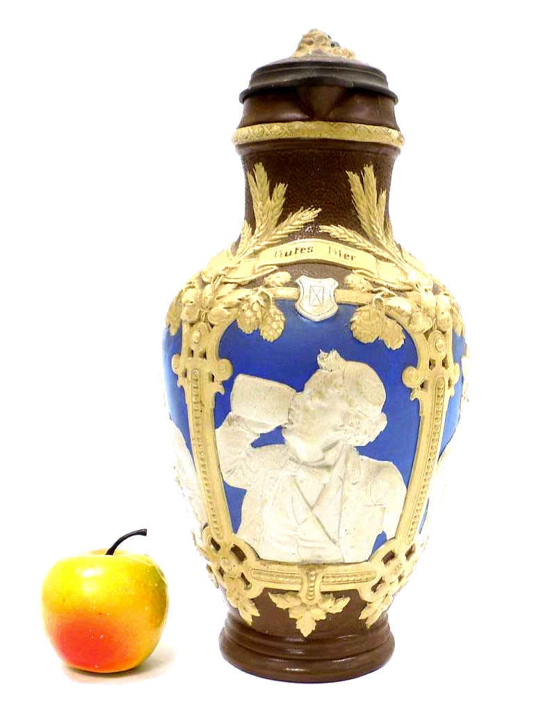 METTLACH No 1736 FOUR PANELS MEN BEER STEIN: Mettlach No 1736 Four Panels of Men Relief Pottery Beer Stein Tankard. 3 Liter with Blue Brown and Cream Glaze. Translation Reads: Good Beer In A Country Brings Joy To All Classes. Figural Hops Lid wi