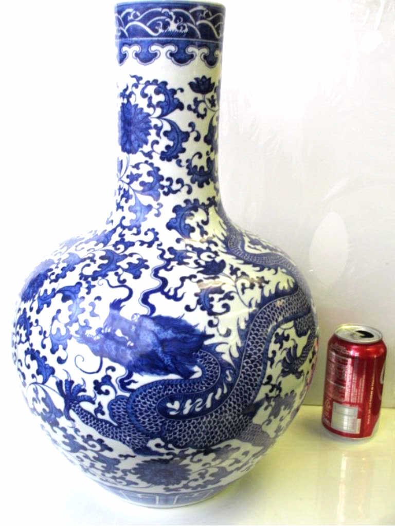 QIAN LONG FORM CHINESE DRAGON VASE: Large Chinese porcelain blue & white bottle vase. Stylized flowers & waves surrounding wrap aroung dragon. Spurious Qian long underglaze mark. H 18" x W 12".