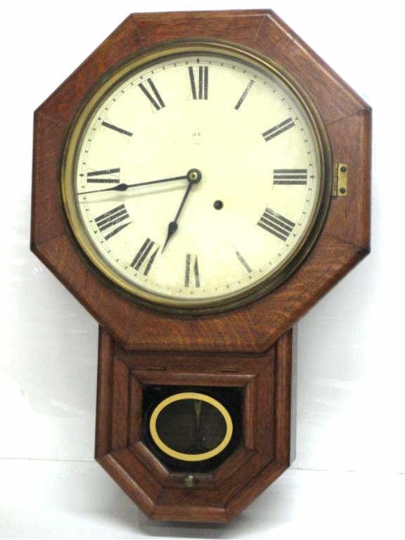 SETH THOMAS OAK SCHOOL HOUSE WALL CLOCK: Seth Thomas tiger oak school house wall clock . Original eglomise window. With key & brass pendulum. H 24" x L 16". Working order.