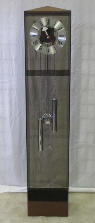 MIDCENTURY MODERNIST HOWARD MILLER TALL CASE CLOCK: Midcentury Modernist Howard Miller designer Lucite tall case chime clock . Rosewood pyramid top & base. Original silver tone chain, pendulum & weights. H 60" x 8" x 12"