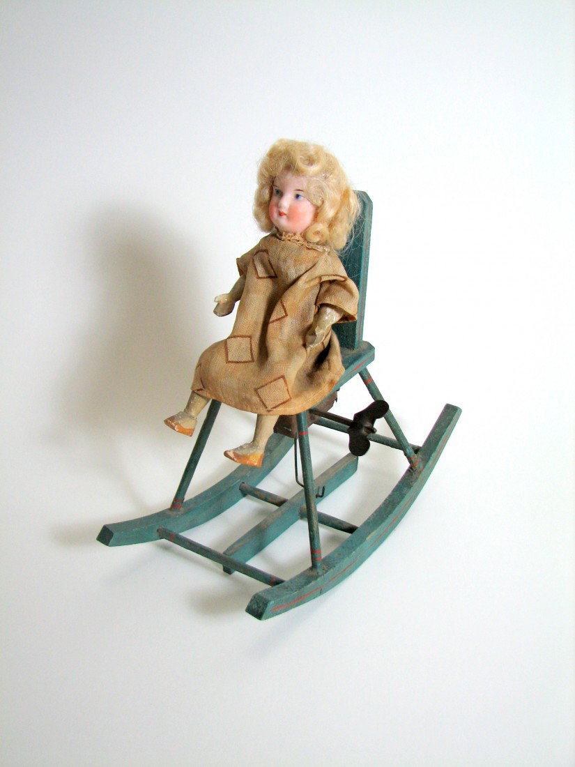 Victorian Mechanical Doll in Rocking Chair: 19th Century baby doll rocking toy. The doll has a hand-painted porcelain face, human hair, and wooden appendages. She perches atop a fully operational wind-up rocking high chair. When wound the chair