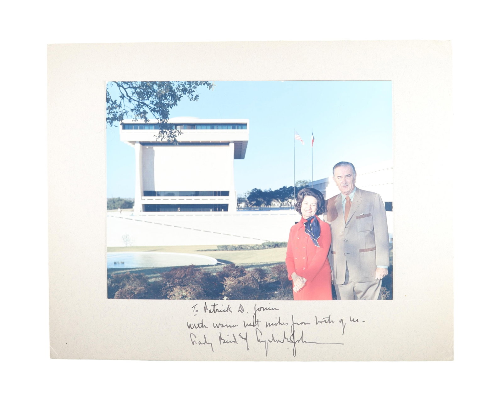LADY BIRD JOHNSON SIGNED PHOTOGRAPH WITH LBJ BEFORE THE PRESIDENTIAL LIBRARY: LADY BIRD JOHNSON SIGNED WITH LBJ BEFORE THE PRESIDENTIAL LIBRARY, INSCRIBED TO PATRICK D. GORRIN A color depicting Lady Bird Johnson and President Lyndon B. Johnson standing together before what appe