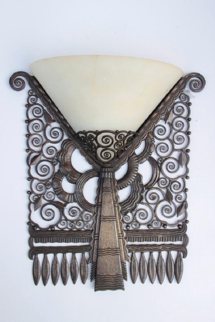 Marcel BERGUE (1888-?), vers 1925. Rare et importante: Marcel BERGUE (1888-?), vers 1925. Rare et importante applique à diffuseur - cornet arrondi en albâtre disposé dans une structure en fer forgé, à décor de volutes, palmes et feuilles stylisées.