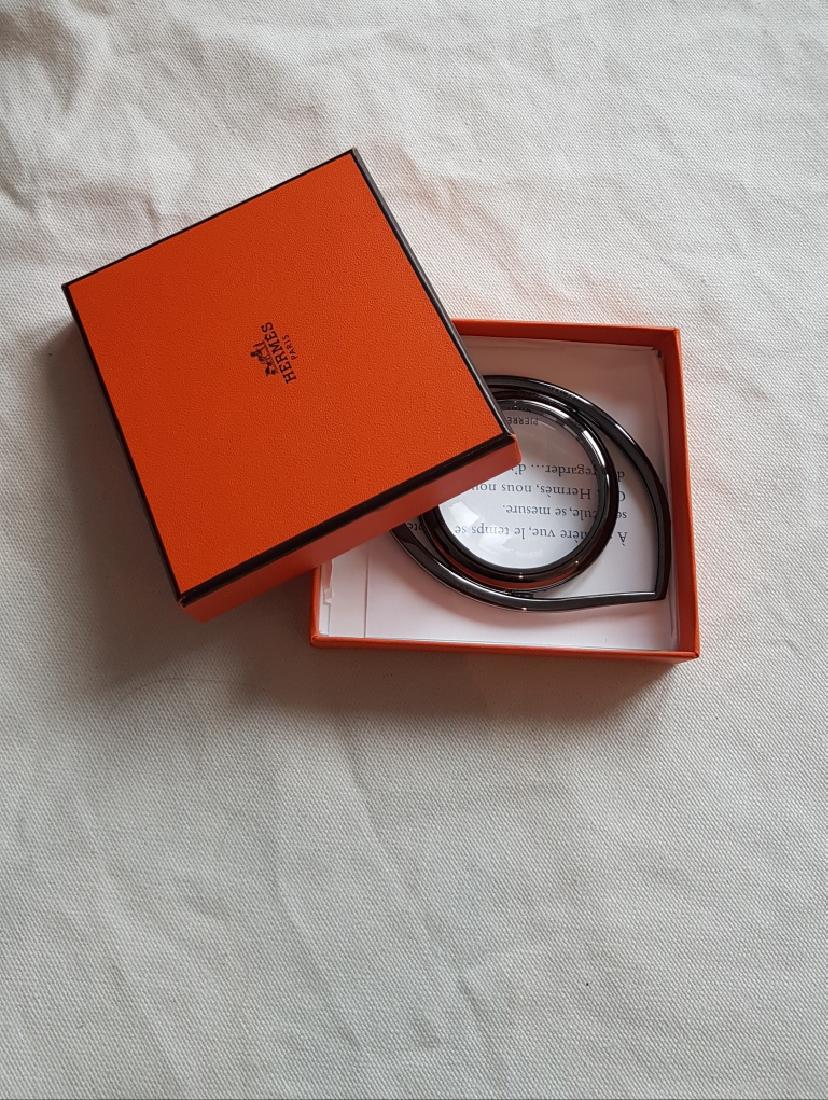 HERMES Paris Loupe en métal noirci « Oeil de Cléopatre: HERMES Paris Loupe en métal noirci « Oeil de Cléopatre « , édition limitée par sa couleur canon de fusil. Largeur 10 cm Hauteur 7 cm Très bon état dans sa boite d’origine