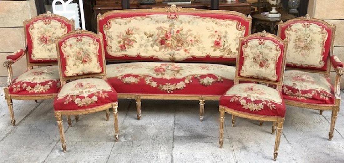 Salon en bois mouluré et doré comprenant un canapé,: Salon en bois mouluré et doré comprenant un canapé, deux fauteuils, deux chaises et un tabouret de piano pivotant. Garniture de tapisserie à décor floral polychrome sur fond rouge. Style Louis XV