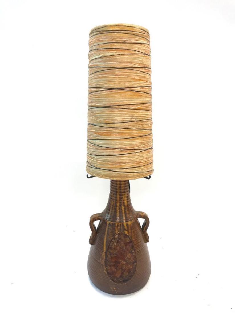 ACCOLAY, vers 1970 Lampe à cache-ampoules en: ACCOLAY, vers 1970 Lampe à cache-ampoules en résine sur piétement en céramique brune à décor de deux anses et d'un cabochon Signé dessous H :98 cm