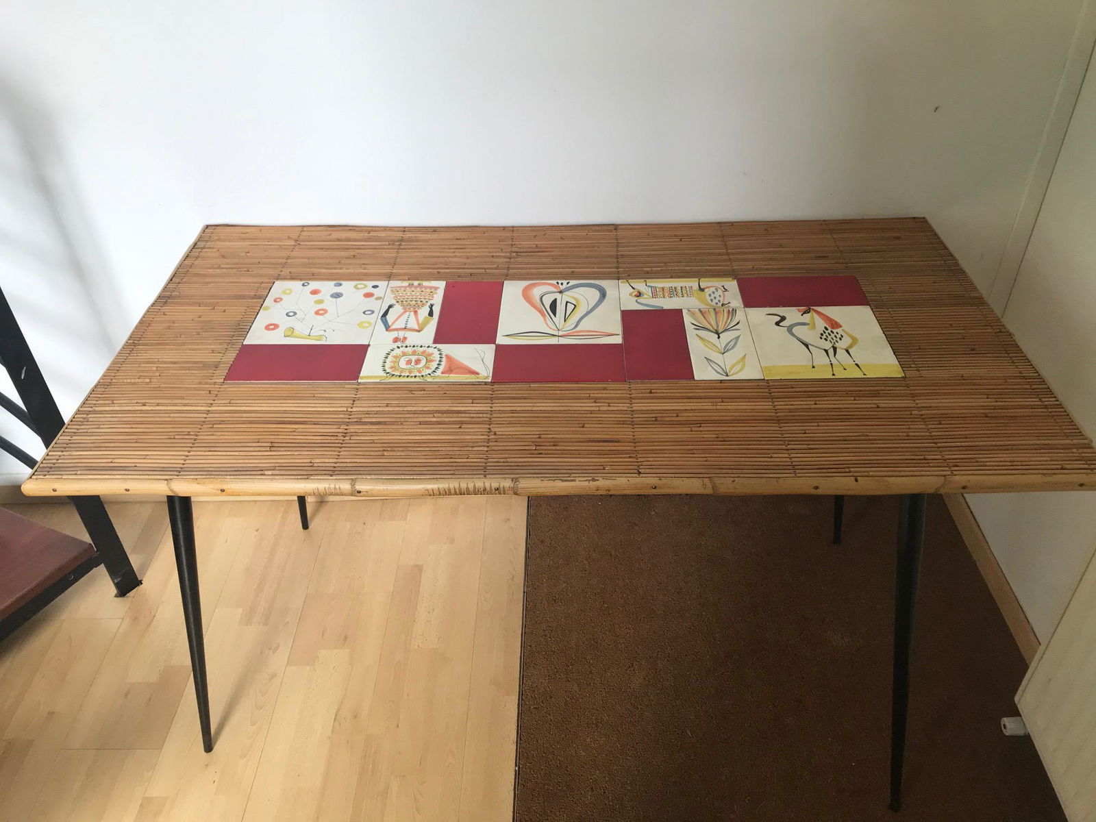 Roger Capron, vers 1950 Rare table de salle à : Roger Capron, vers 1950 Rare table de salle à manger à plateau rectangulaire en jonc de rotin et bande de carreaux de céramique à décor fantaisiste dégagé sur fond blanc, reposant sur qua