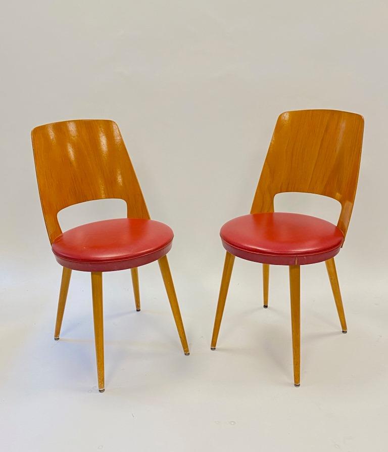 BAUMANN (XXe siècle) Paire de chaises en: BAUMANN (XXe siècle) Paire de chaises en contreplaqué moulé et assise en cuir rouge reposant sur 4 pieds faisceau H : 81 cm