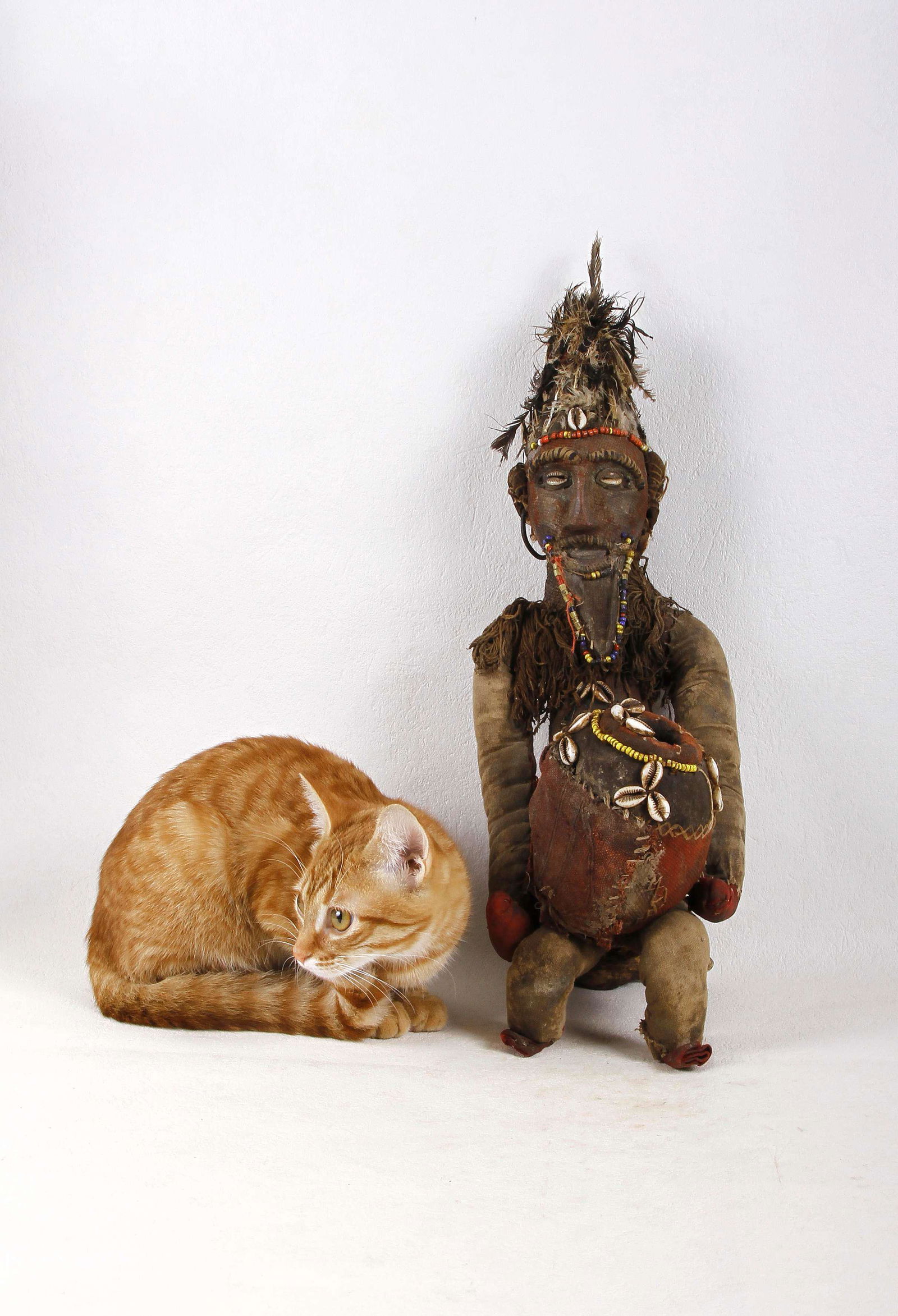 Statue en bois, perles, cauris, tissu et plumes: Statue en bois, perles, cauris, tissu et plumes figurant un porteur de coupe à longue barbe. L'ensemble est recouvert de tissu et orné de perles, plumes et cauris. Style Bembé - Ré