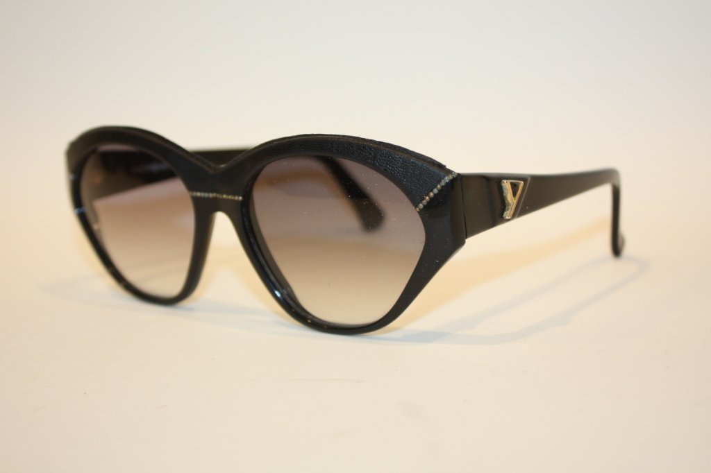 YVES SAINT LAURENT - Paire de lunettes de soleil o: YVES SAINT LAURENT - Paire de lunettes de soleil ornée de cuir noir circa 1980 avec verres d'origine. Très bon état
