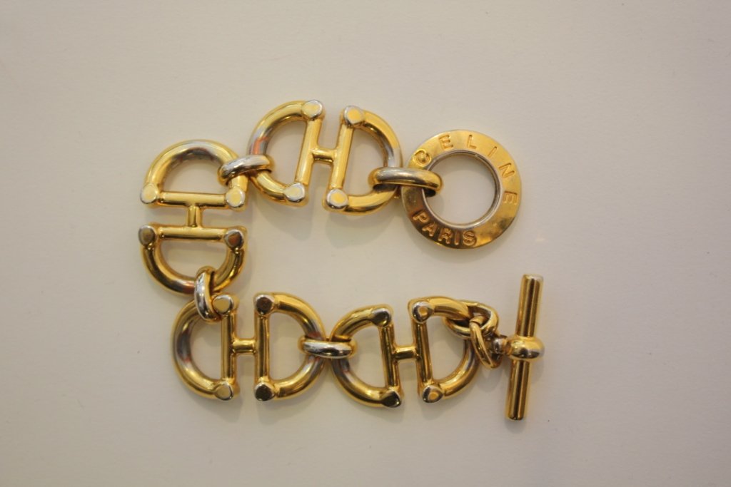 CELINE - Bracelet articulé composé d'anneaux entrel: CELINE - Bracelet articulé composé d'anneaux entrelacés en métal doré , fermoir siglé, très bon état