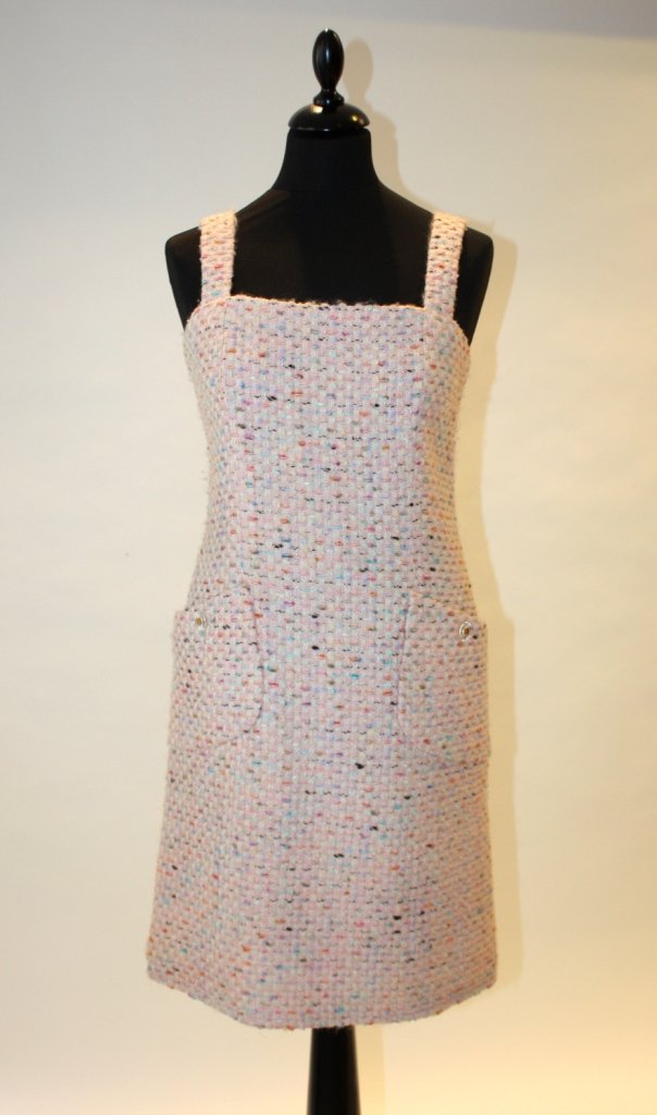 CHANEL - Robe à bretelles en tweed de ton pastel su: CHANEL - Robe à bretelles en tweed de ton pastel sur fond rose pâle. Deux poches appliquées fermant par des boutons siglés en altuglas et métal doré. Taille 40. Parfait état.
