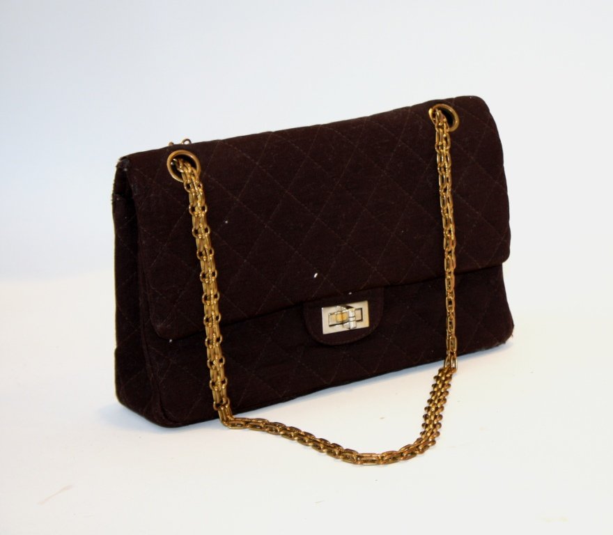 CHANEL - Sac modèle 2.55 en jersey marron. Anse en: CHANEL - Sac modèle 2.55 en jersey marron. Anse en chaînette de métal doré. Etat d'usage. L : 25 cm