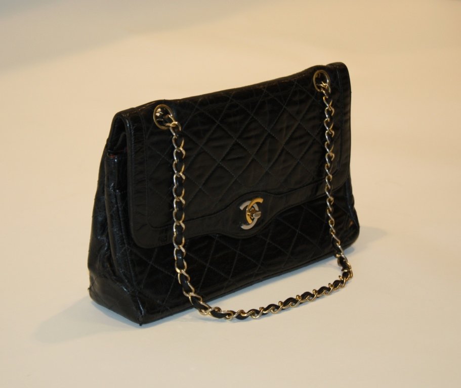 CHANEL - Sac modèle 2.55 en cuir noir matelassé et: CHANEL - Sac modèle 2.55 en cuir noir matelassé et intérieur en cuir rouge. Anse en chaînette de métal doré. Hologramme. Vers 1980. Etat d'usage. Manque au fermoir. L : 26 cm