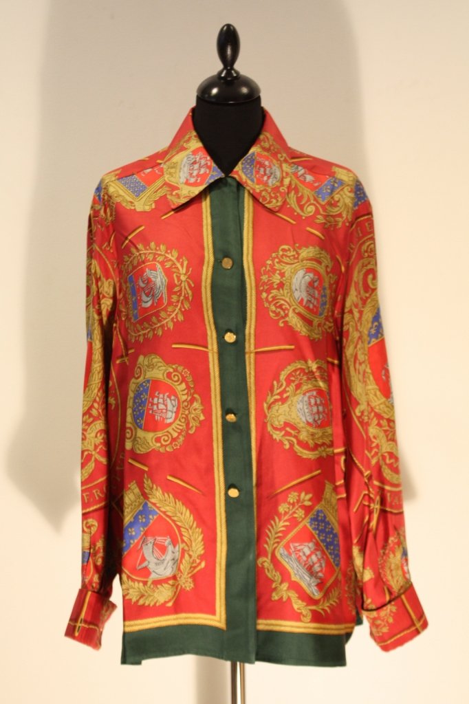 HERMES-Chemise en soie imprimée de blasons ornés d: HERMES-Chemise en soie imprimée de blasons ornés de navires, fond rouge. Taille 46, boutons dorés et siglés. Bon état.