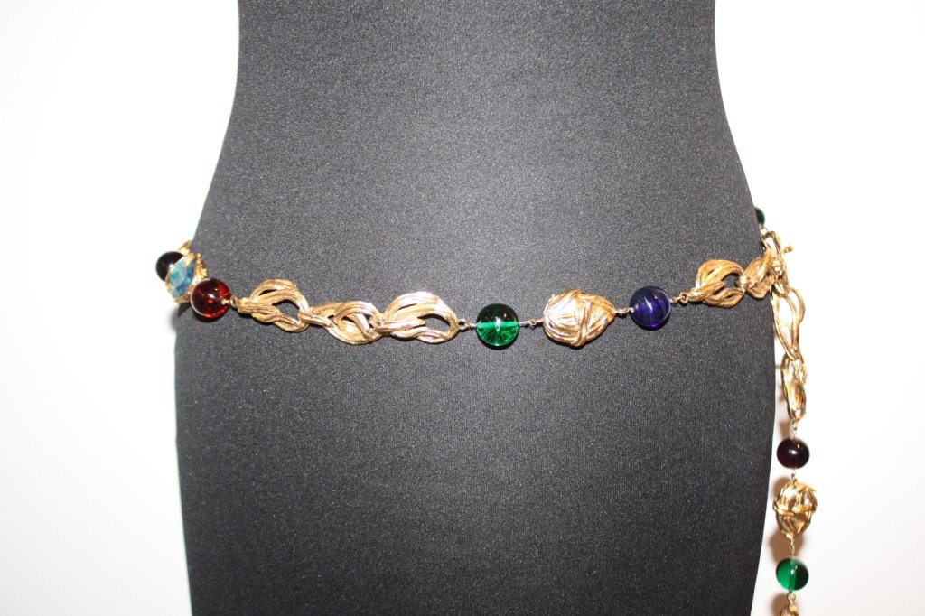 Yves Saint Laurent- Ceinture en anneaux de métal d: Yves Saint Laurent- Ceinture en anneaux de métal doré et perles de verre polychromes, fermoir composé de trois cœurs siglés, vers 1980. Très bon état.