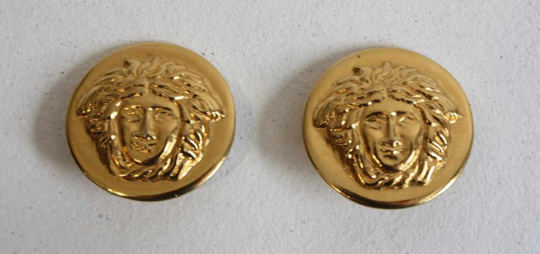 GIANNI VERSACE - Paire de boucles d'oreilles sphériques: GIANNI VERSACE - Paire de boucles d'oreilles sphériques en métal doré à décor de l'emblème de la marque . Bon état