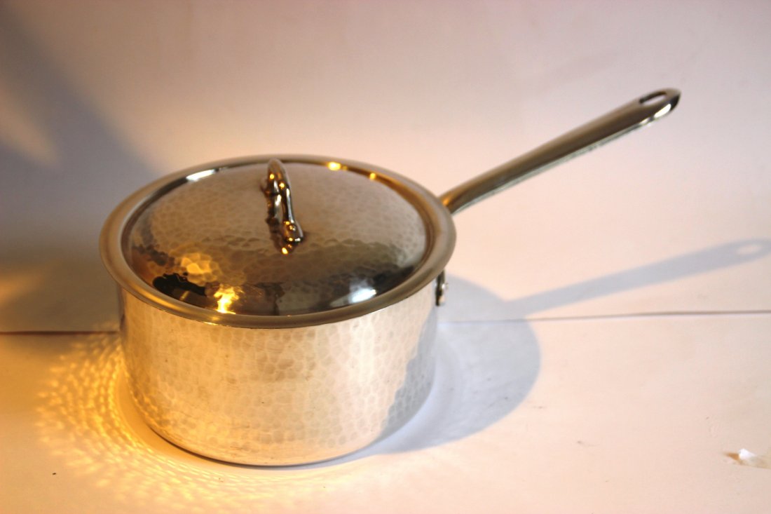 Christian DIOR Casserole en métal martelé et argenté,: Christian DIOR Casserole en métal martelé et argenté, avec son couvercle. Signé dessous L : 32 cm