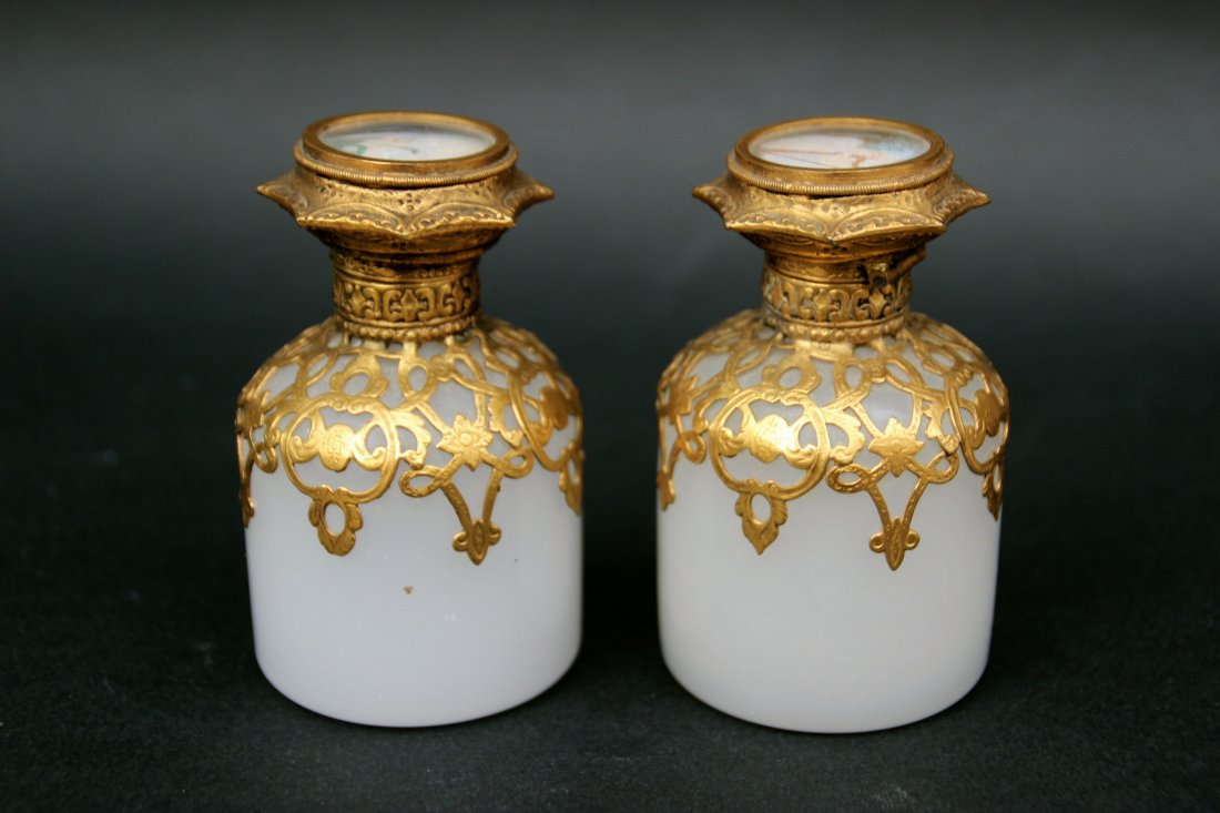 Paire de flacons en opaline: Paire de flacons en opaline blanche à monture en laiton doré insérant une miniature peinte figurant des élégantes sur le couvercle.XIXe siècle.Hauteur : 18 cm