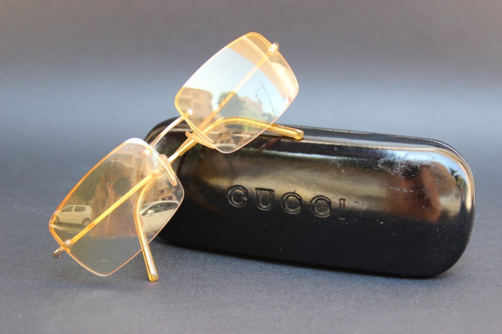 GUCCI Paire de lunettes de soleil pour homme à verres: GUCCI Paire de lunettes de soleil pour homme à verres teintés jaunes, fines branches en métal doré. Etui noir siglé