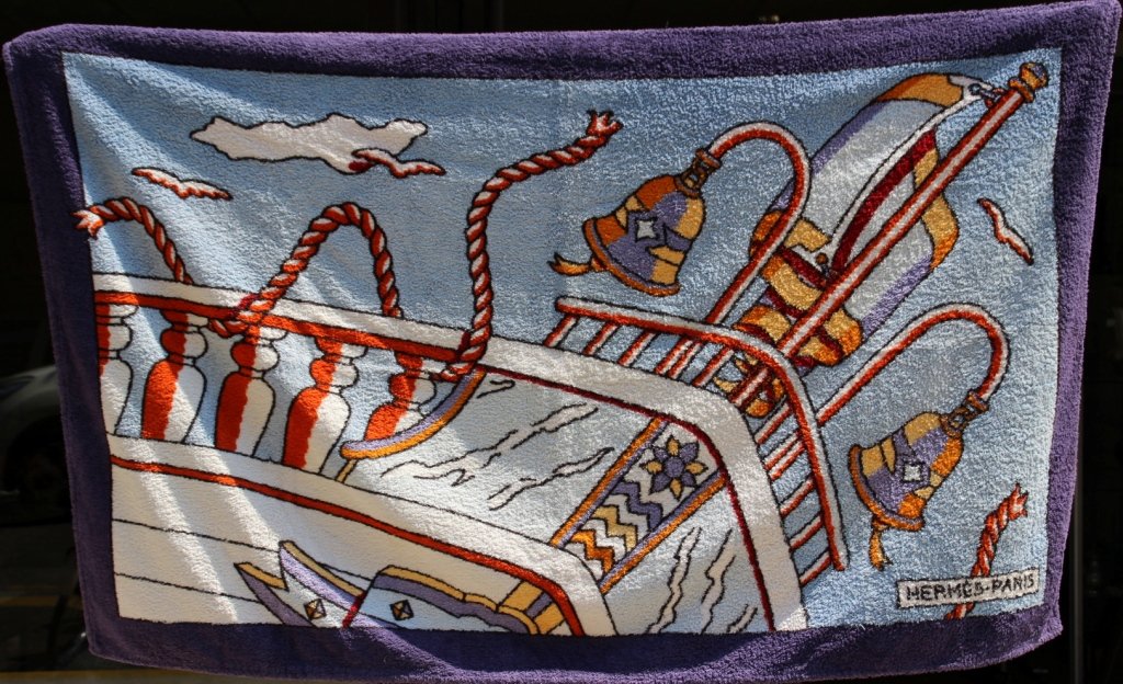 HERMES Serviette en éponge avec motif de proue de: HERMES Serviette en éponge avec motif de proue de bateau sur fond bleu clair, bordure violette Dimensions : 145 x 90 cm Bon état