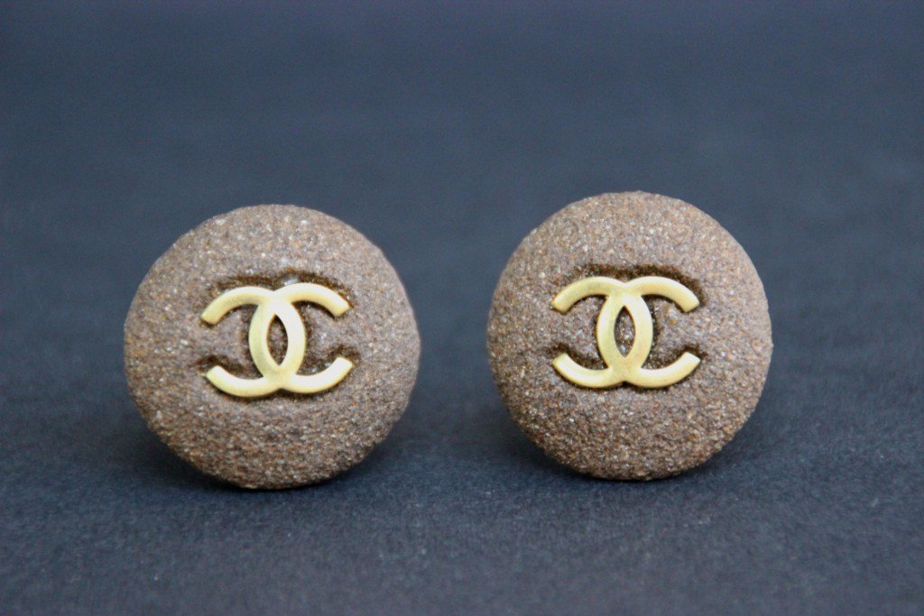 CHANEL Paire de clips d'oreille ronds en terre cuite: CHANEL Paire de clips d'oreille ronds en terre cuite avec sigle de la marque en laiton doré. Bon état.