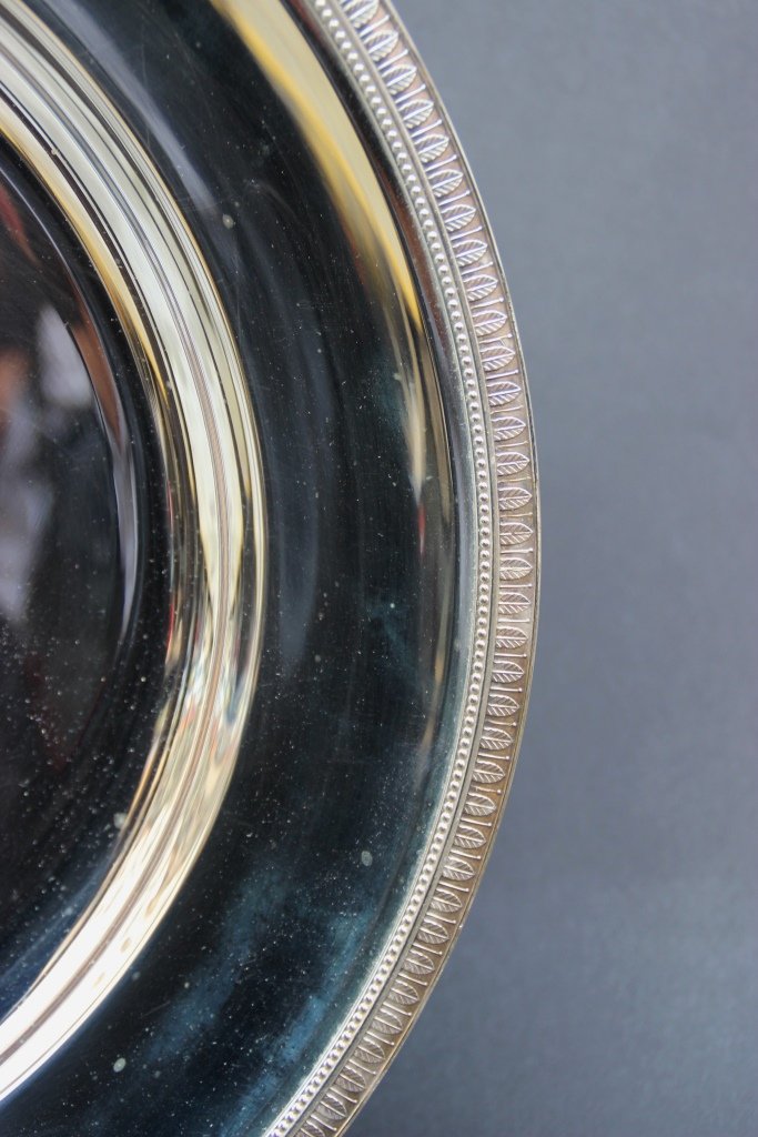 CHRISTOFLE Plat rond en métal argenté décoré d'une: CHRISTOFLE Plat rond en métal argenté décoré d'une frise de feuilles d'acanthes D : 40 cm Etat neuf dans feutrine