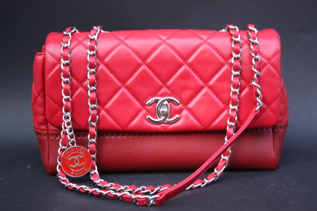 CHANEL Sac en agneau matelassé rouge cerise ,fond en: CHANEL Sac en agneau matelassé rouge cerise ,fond en cuir grainé rouge foncé, garniture en métal, bandoulière en entrelacs de cuir rouge sur métal 26 x 17 x 10 cm Bon état