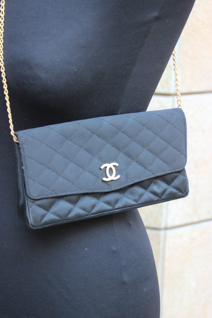 CHANEL Pochette en tissu matelassé noir, fermoir siglé: CHANEL Pochette en tissu matelassé noir, fermoir siglé en strass, fine bandoulière en métal doré Etat d'usage