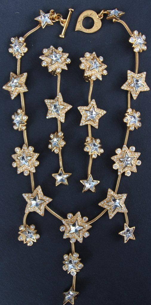 YVES SAINT LAURENT Parure composée d'un collier et: YVES SAINT LAURENT Parure composée d'un collier et d'une paire de boucles d'oreilles en métal doré à décor d'étoiles de strass blanc Bon état
