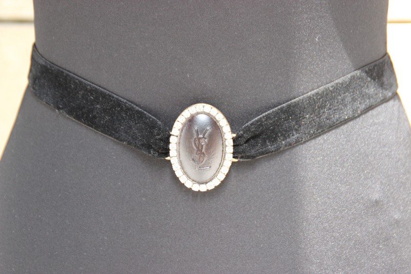 YVES SAINT LAURENT Rive gauche Collier composé d'un: YVES SAINT LAURENT Rive gauche Collier composé d'un médaillon Siglé sur un ruban de velours noir Bon état (dans sa boite)