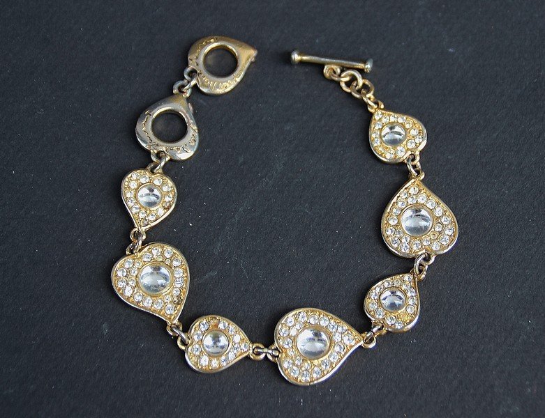 YVES SAINT LAURENT Bracelet en métal doré Composé de: YVES SAINT LAURENT Bracelet en métal doré Composé de cœurs strassés Etat d'usage (manque un strass)
