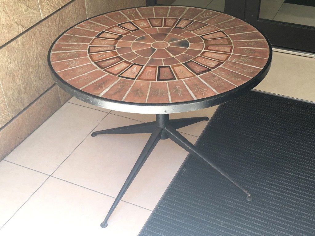 Roger CAPRON(1922-2006) - vers 1965. Guéridon à plateau: Roger CAPRON(1922-2006) - vers 1965. Guéridon à plateau circulaire en céramique à décor "Herbier" sur fond ocre et terre vernissée, reposant sur un piètement en quatre parties obliques en méta