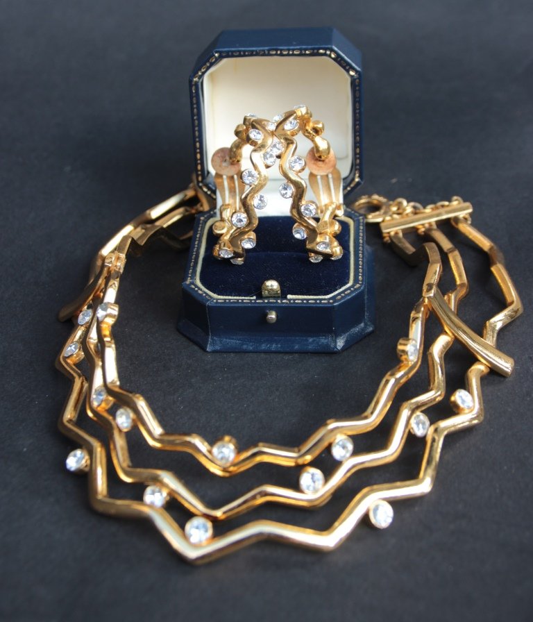 YVES SAINT LAURENT Collier ras de cou en métal doré et: YVES SAINT LAURENT Collier ras de cou en métal doré et strass blanc. On y joint une paire de boucles d’oreilles à l’identique. Bon état