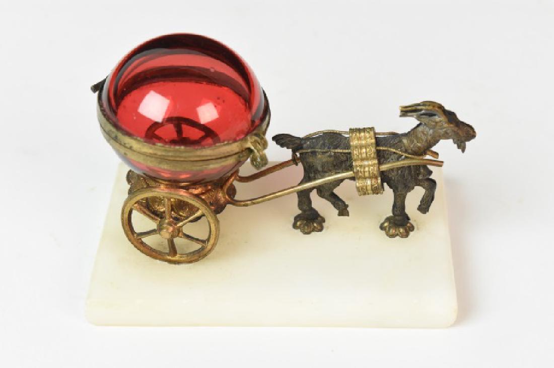 Antique Goat Pulling Cranberry Glass Carriage: This antique goat has an important job pulling this fragile cranberry glass carriage. Believed to be a decorative pill box this fun piece is mounted to a marble surface. It is in good condition with a