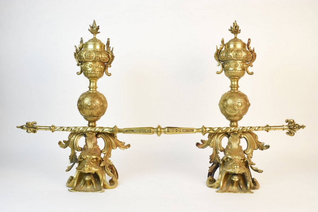 French Style Neoclassical Andirons: Highly detailed French style neoclassical andirons with lions head feet, a spherical center and trophy style finial. This metal pair of andirons are very heavy. Each piece is in good used condition wi