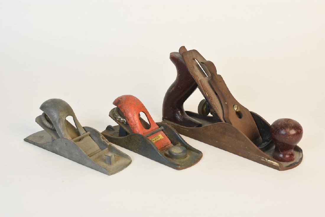 Woodworking Block Planes Including Stanley: A trio of wooden hand planes including one marked "Stanley H1247 Made USA." All items show significant rust build up; surface scratches; loss of paint; and dust residue. The largest plane measures app