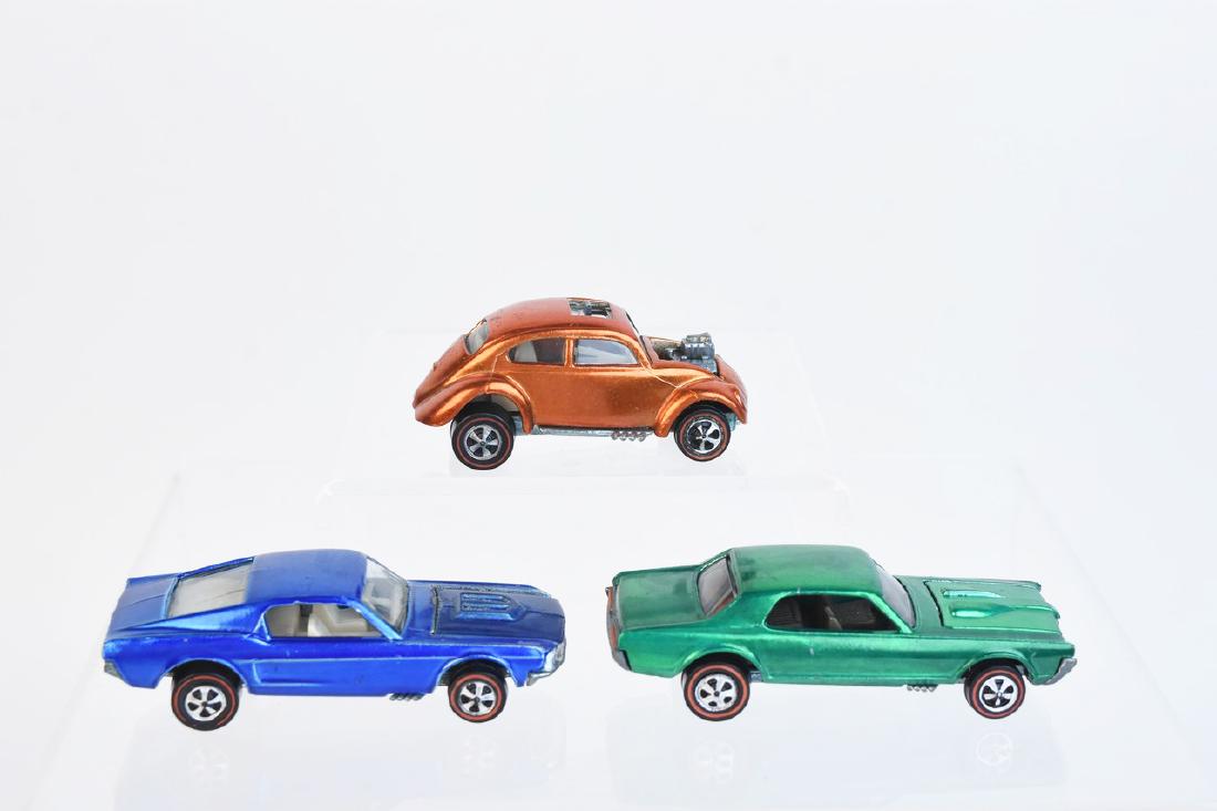 1968 Redline Hot Wheels Cars: A trio of Hot Wheels redline series 1968 cars including an orange Volkswagen. Also included is a blue Custom Mustang with clear glass & white interior; and a green Custom Cougar with dark windows & da