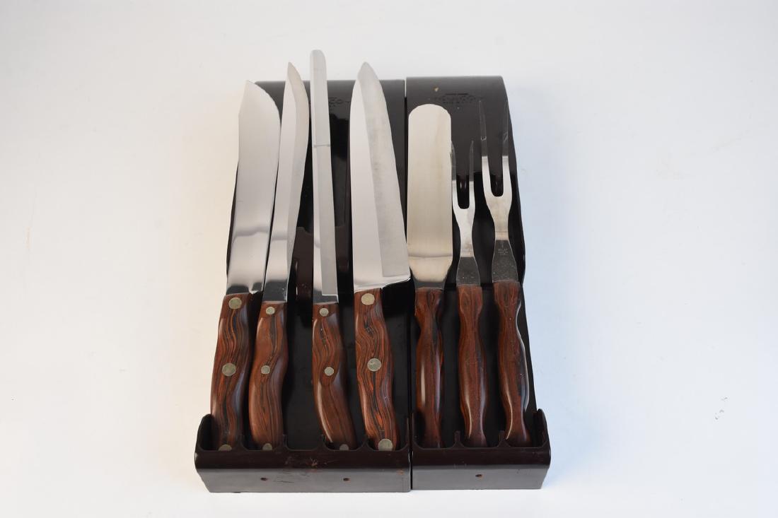 Vintage Cutco Knife and Serving Sets: A pair of Cutco sets with seven utensils and knives. The pieces are presented in two brown plastic caddy mounts for wall or drawers. The pieces include brown Thomas Lamb handles with stainless steel b