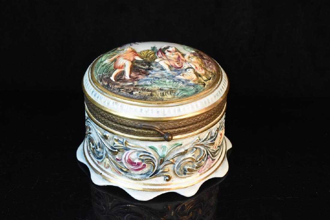 R. Capodimonte Italy Porcelain Box: A circular trinket box by R. Capodimonte of Italy. Features a brass tone band with latch closure. Marked to its underside "G. B. R. Capodimonte 1535/415 Italy"; light surface wear and loss of paint. M