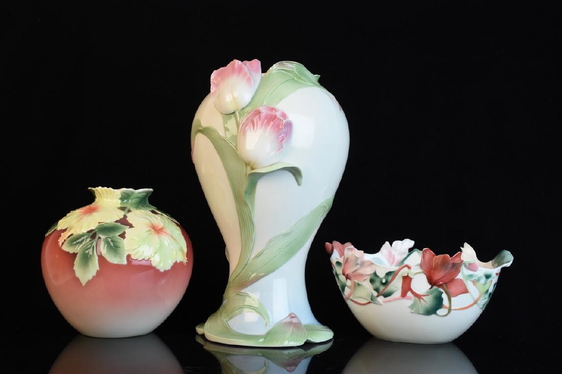 Franz Porcelain Vases and Bowl: A selection of three hand painted Franz decorative porcelain in its original packaging. The designs include a cyclamen lattice sculptured centerpiece bowl (1098), a tulip sculptured tall vase (494), a