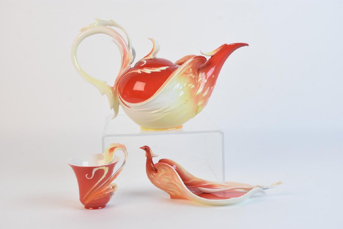 Franz "Phoenician Flight" Tea Set: A collection of hand painted Franz porcelain items in the "Phoenician Flight" Phoenix bird design. The set includes A teapot with removable lid (1706), a teacup with saucer (1739), and decorative (175