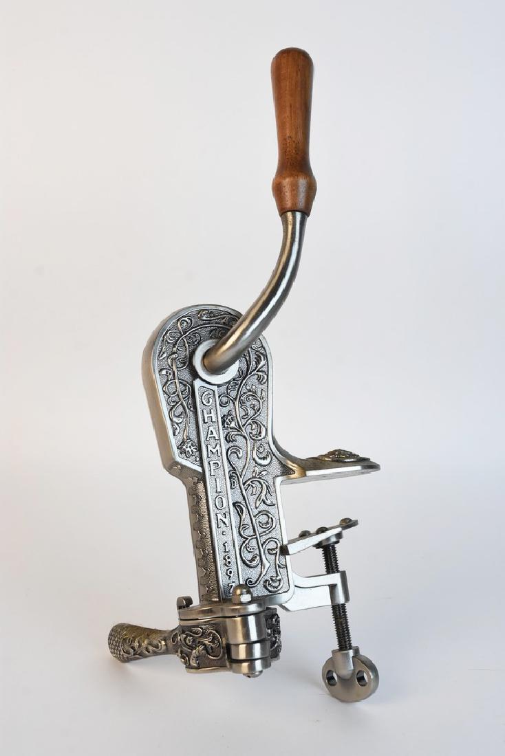 Champion Nickle Plated Wine Opener: A wine bottle opener that mounts to a bar edge. It is comprised of cast metal with relief foliate details. It includes an attached wood handle and is marked to its side "Champion 1889." Some dust resi
