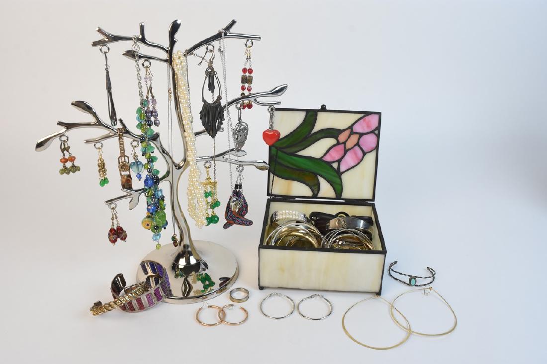 Assorted Costume Jewlery w/ Storage: An assortment of costume jewelry in a stained glass trinket box & a silver tone metal tree. Items include brands such as Honora & Monet; and items such as bracelets, earrings, and necklaces. Condition