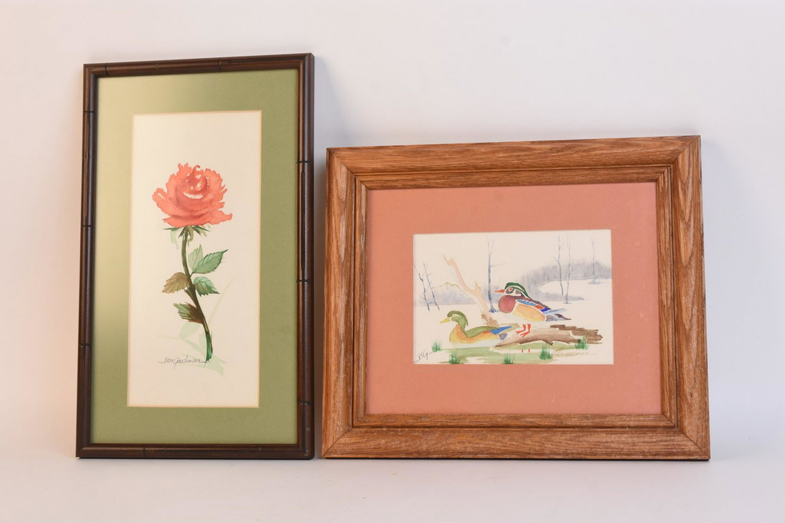 Ben Goodman Artwork: A pair of framed pieces of art by Missouri artist Ben Goodman. The pieces are both presented beneath glass and paper matting; and encompassed by a wood frame with hanging fixtures affixed to the verso