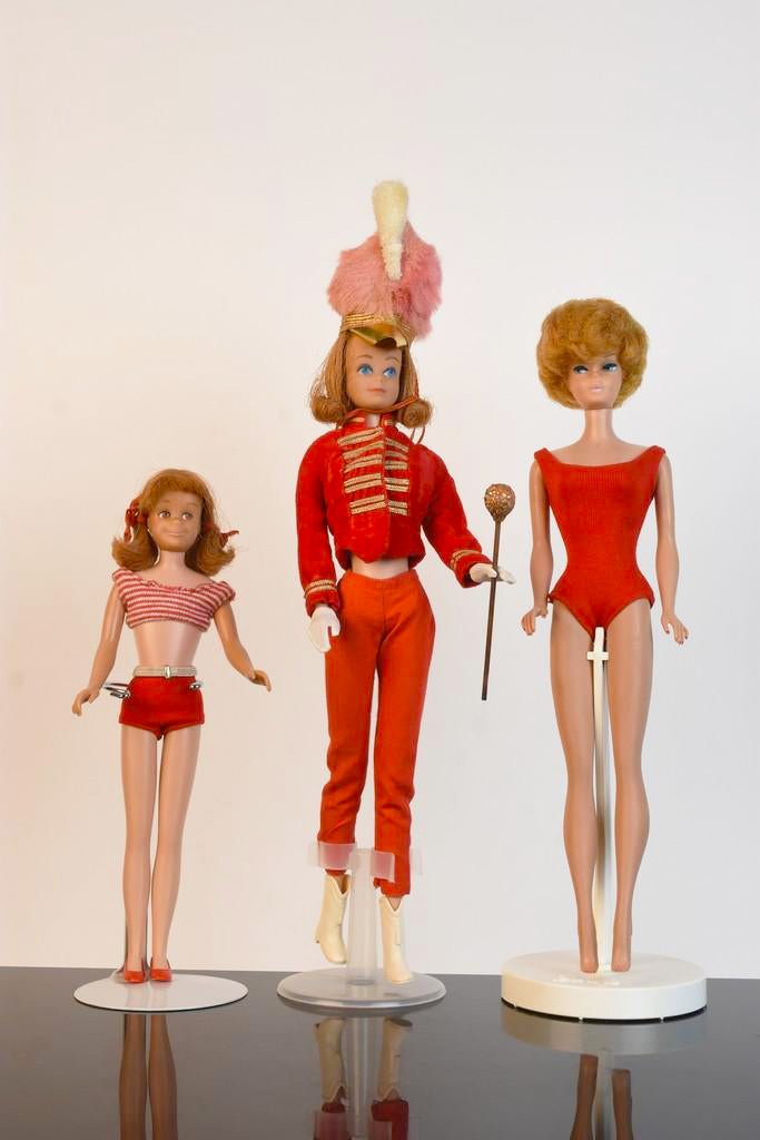 1960s Midge, Scooter & Bubble Cut Barbie: A trio of Mattel dolls including a 1962 Bubble Cut Barbie (blond) in red bathing suit; a 1963 Midge (titan) in #875 Majorette outfit including baton; and a 1965 Scooter (titan). Some discoloration and